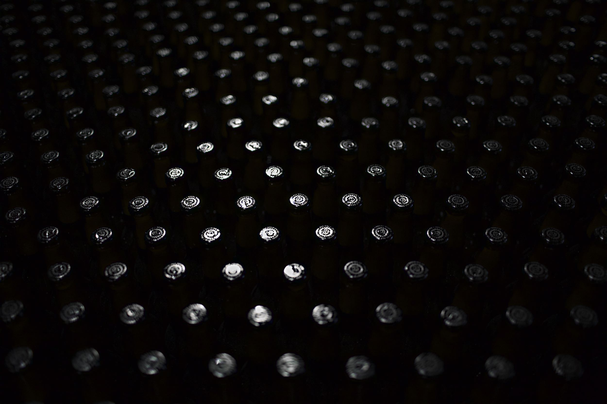 Jody Horton Photography - Real Ale beer bottlecaps shine in the darkness of the bottling plant.