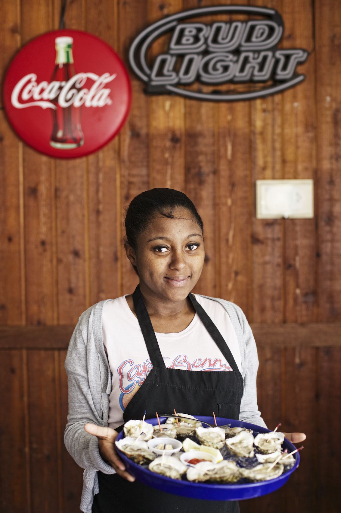 Jody Horton Photography - Waitress with black apron holding blue tray of raw oysters.