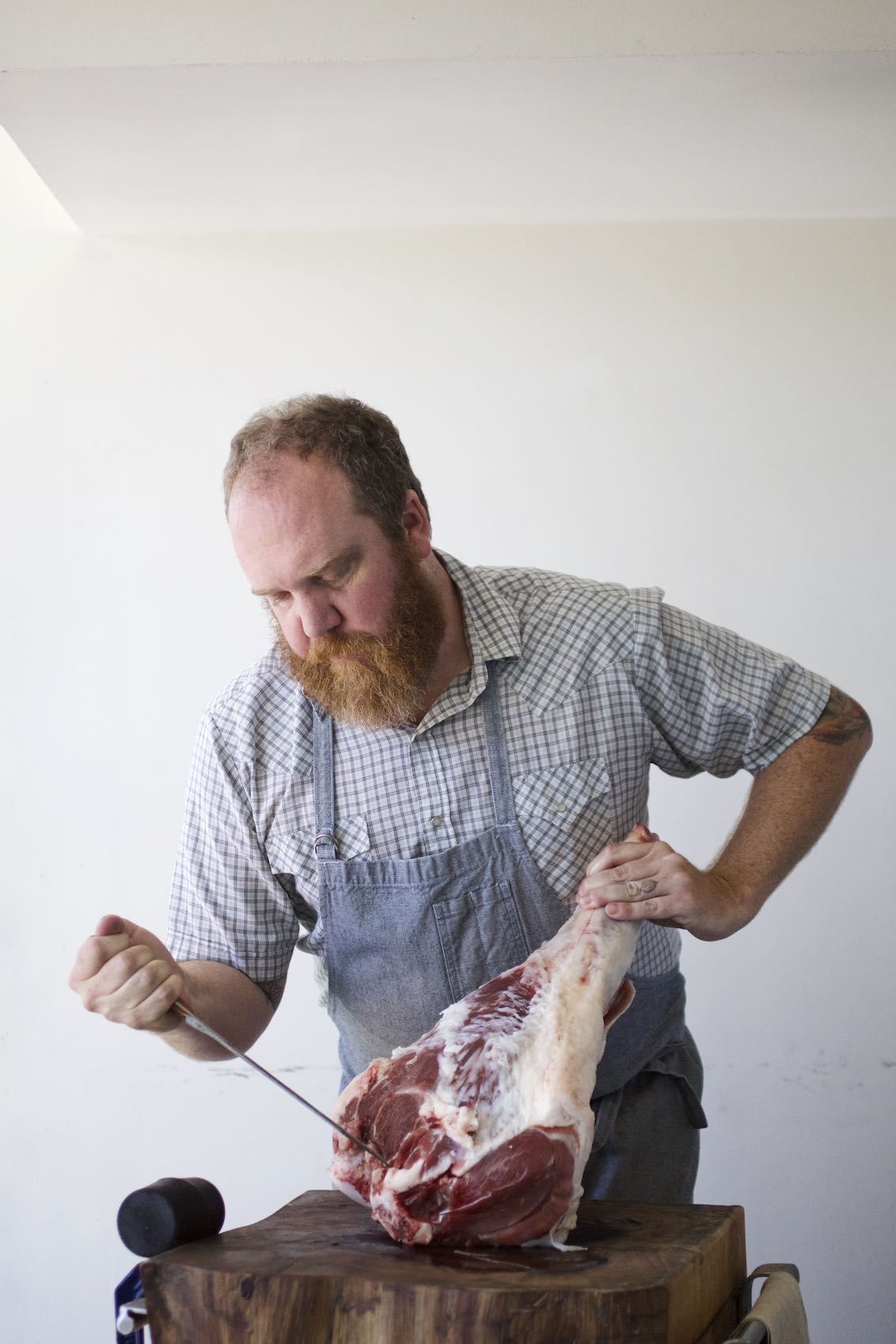 Jody Horton Photography - Dai Due chef carving leg of meat on a wood cutting board. 