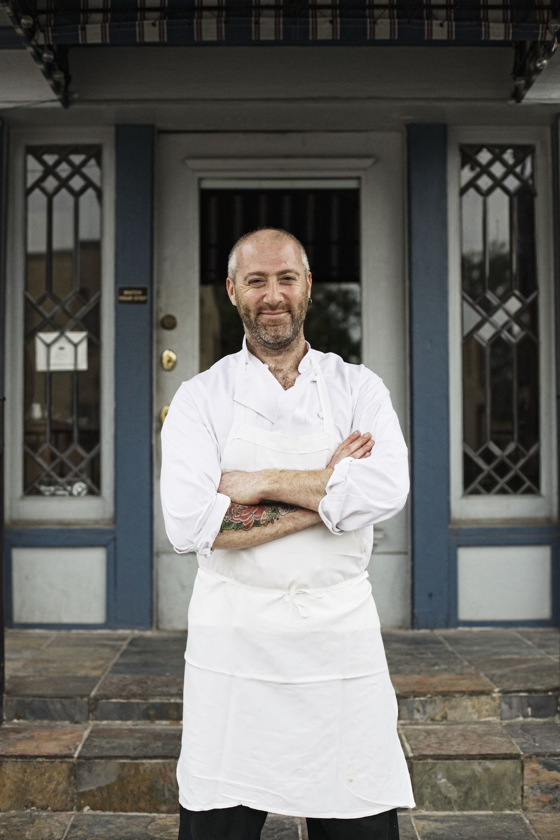 Jody Horton Photography - Chef in uniform proudly standing outside storefront.