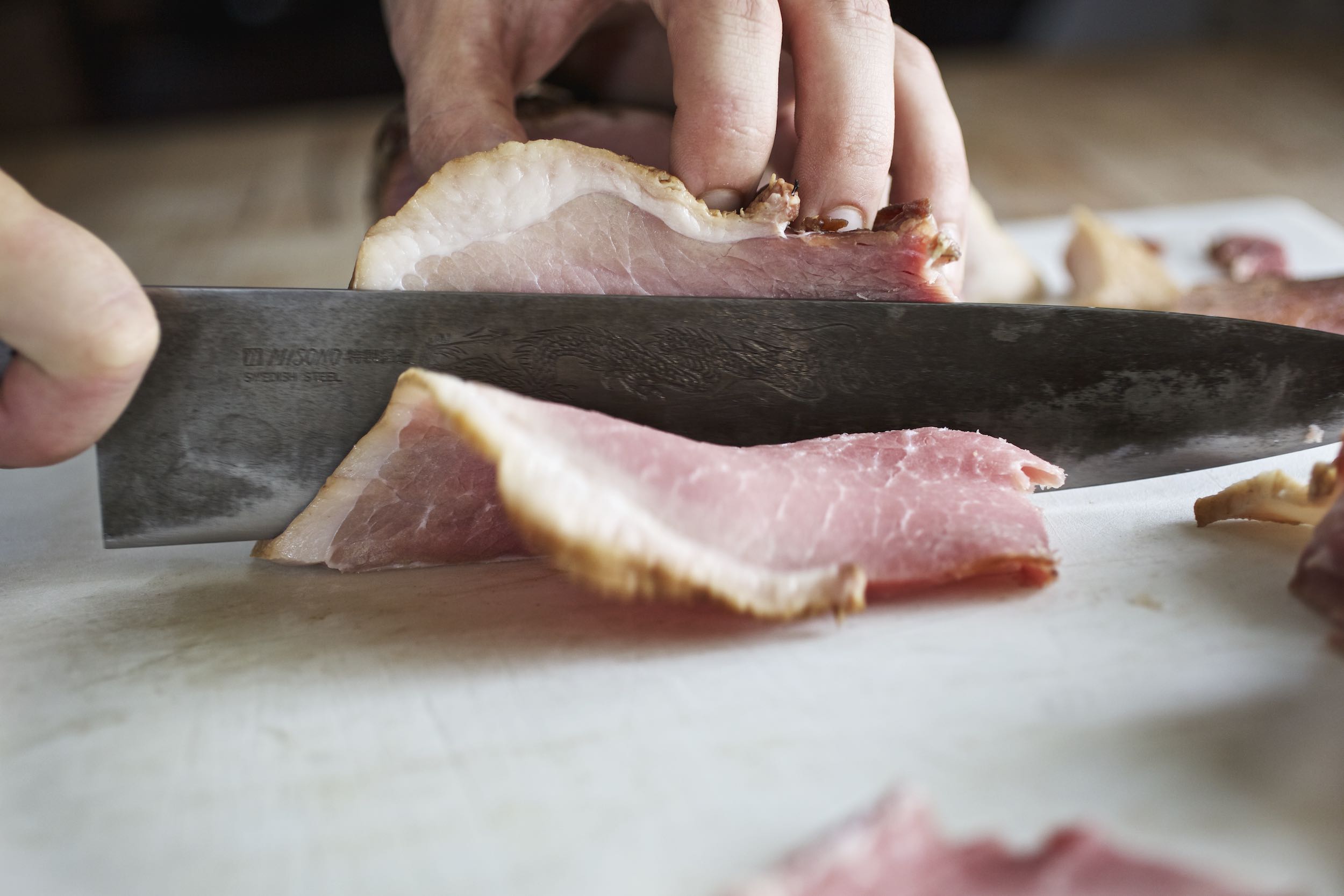 Jody Horton Photography - Chef knife thinly slicing cured meat. 
