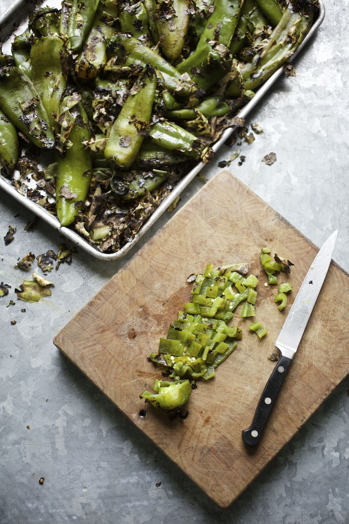 Jody Horton Photography - Whole and diced roasted green chili peppers on a metal prep table.