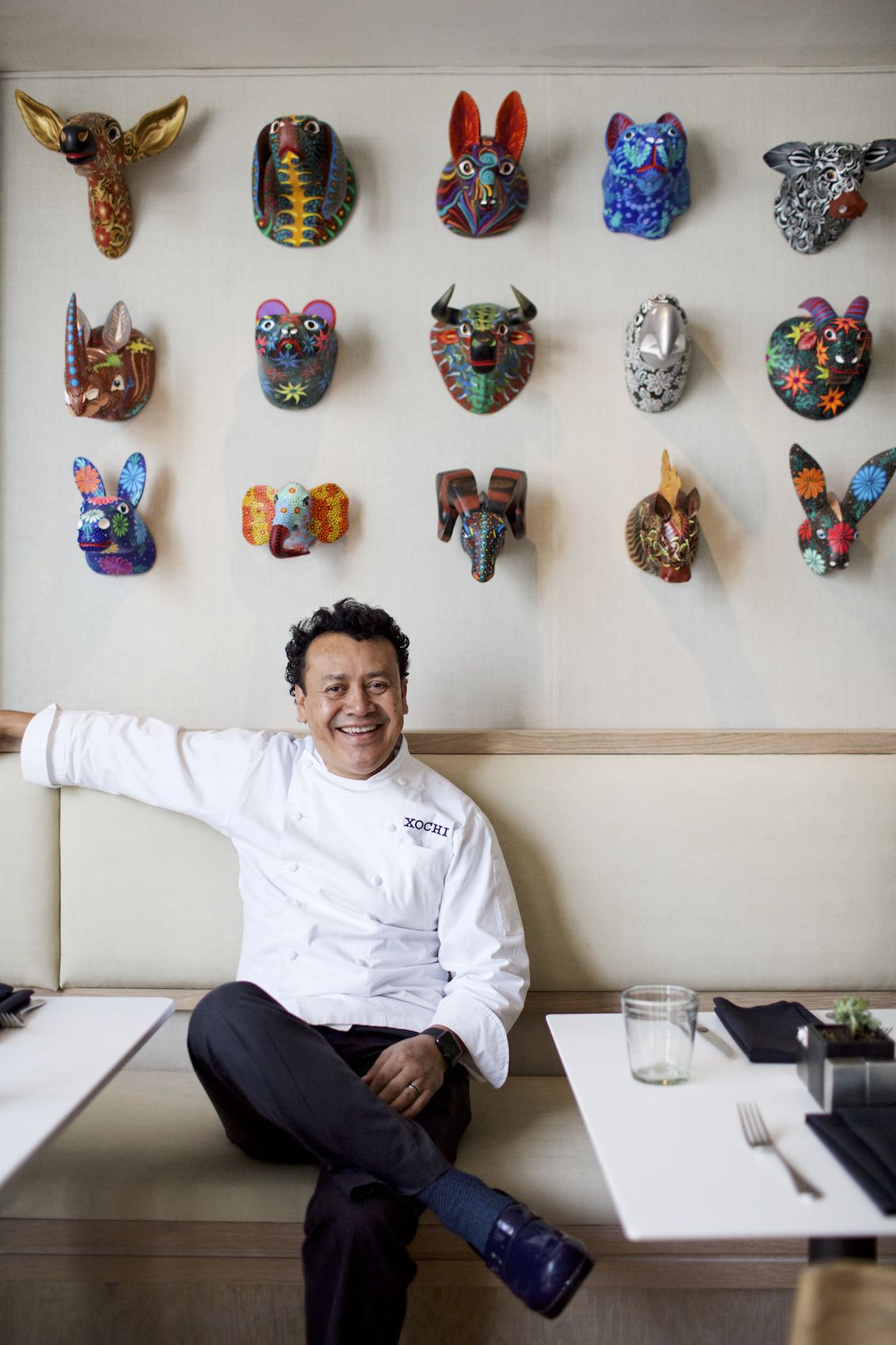 Jody Horton Photography - Chef sitting at a booth in a restaurant dining room with colorful, Mexican artwork.