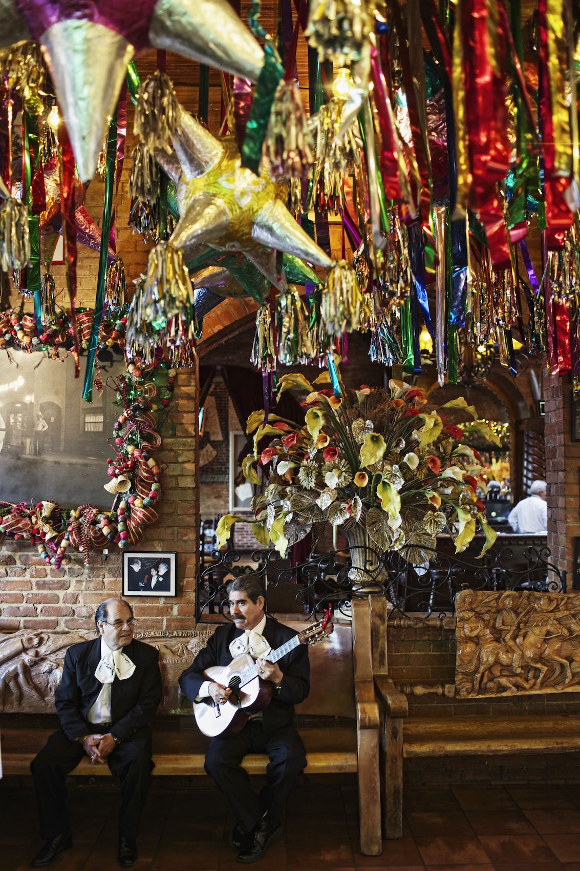 Jody Horton Photography - Two mariachi men sitting under the colorful tassels of a Mexican restaurant. 