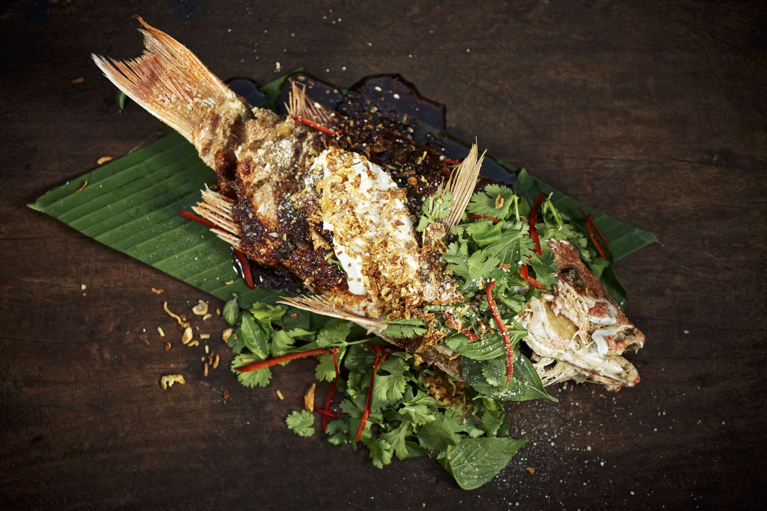 Jody Horton Photography - Whole cooked redfish on banana leaf with herbs and sauces. 