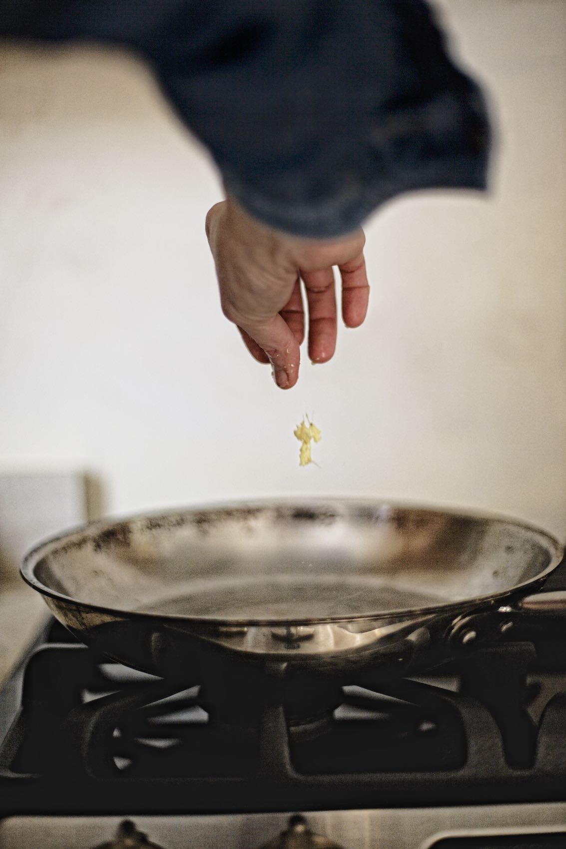 Jody Horton Photography - Chef hand throwing diced ginger in large skillet on stove top. 