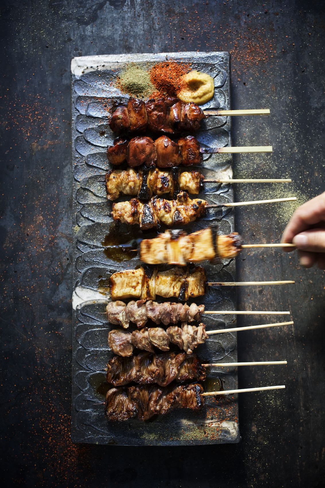 Jody Horton Photography - Assorted kebabs presented on stone slab with colorful spices. 