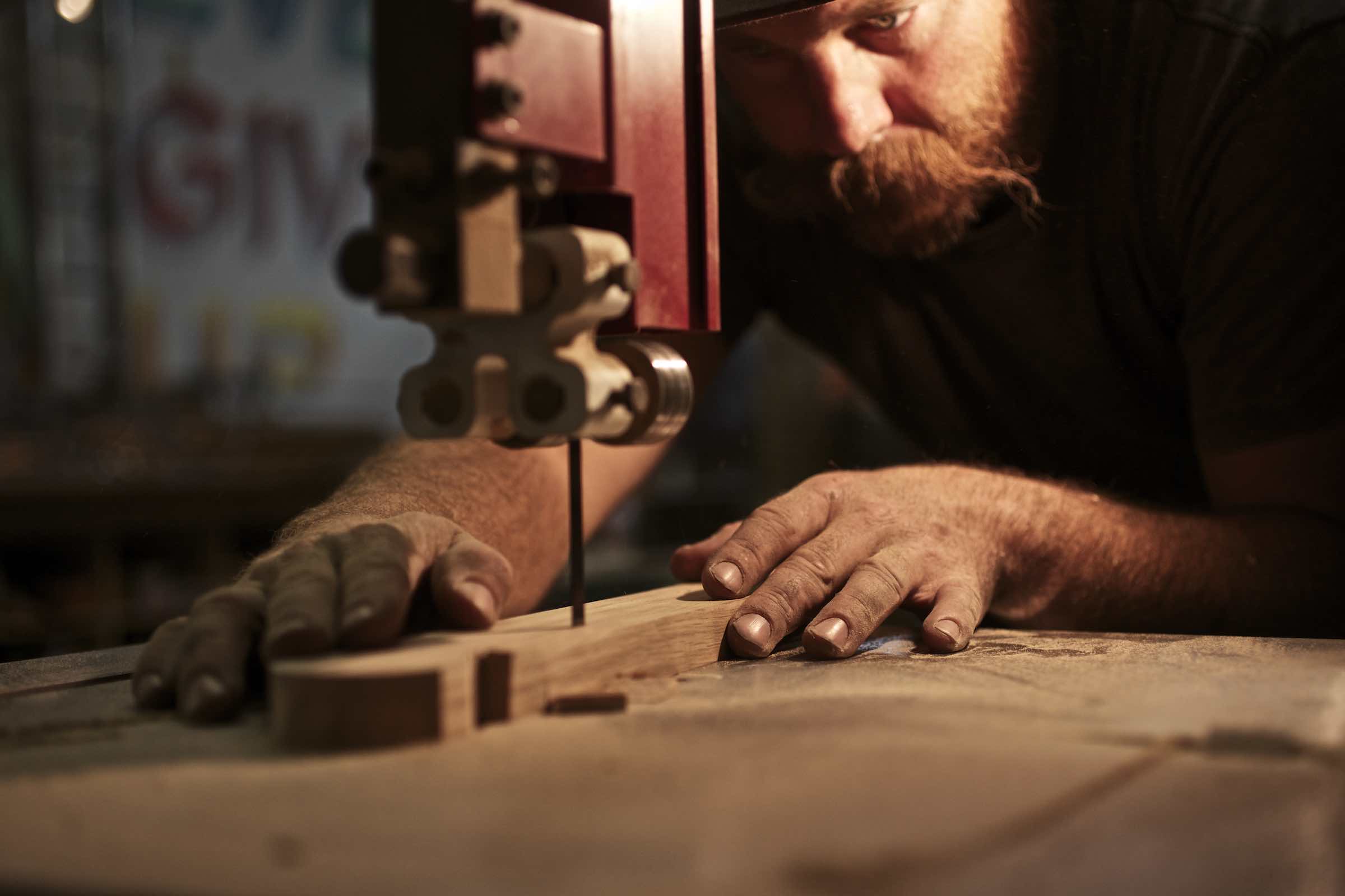 Jody Horton Photography - Woodworker pushing a slab of wood through an electric saw. 