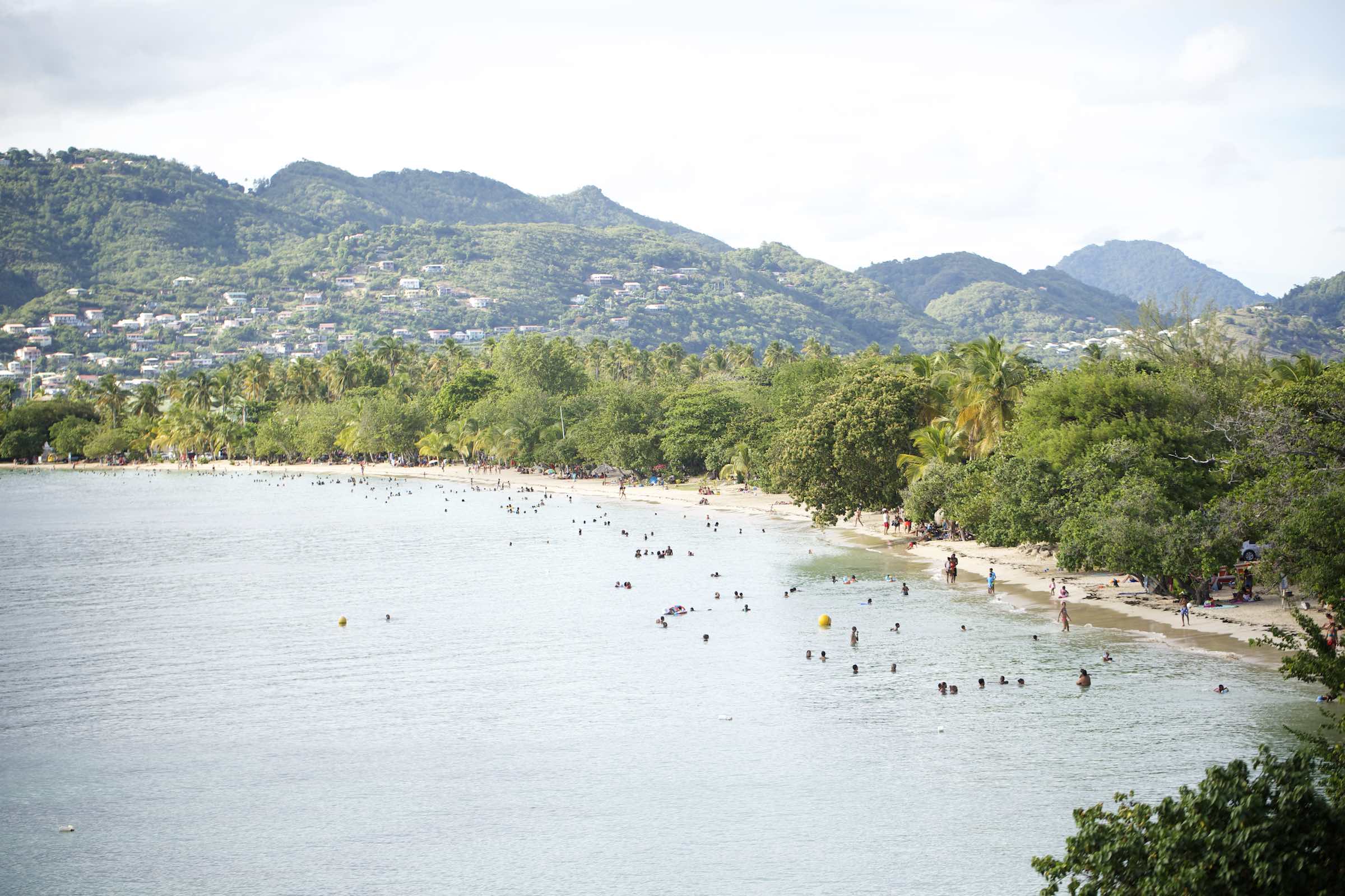 Jody Horton Photography - A busy beach with clear waters lined with lush vegetation and mountains.