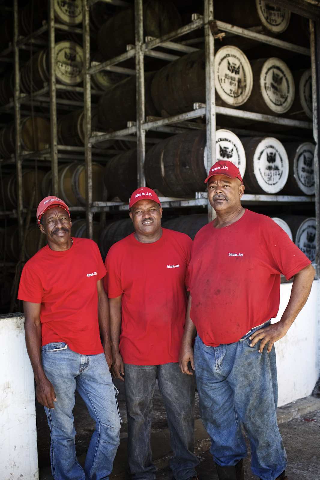 Jody Horton Photography - Workers red labeled caps and shirts standing against stacked wood barrels. 