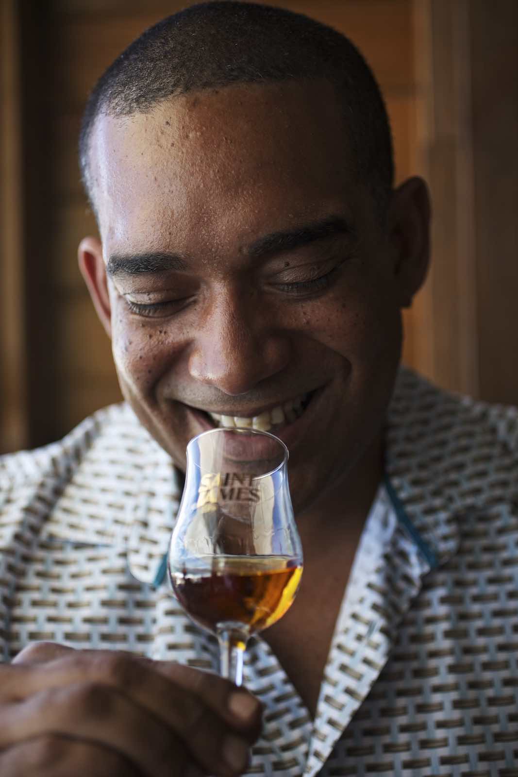 Jody Horton Photography - Man in a patterned shirt smiling while holding a glass of rum. 