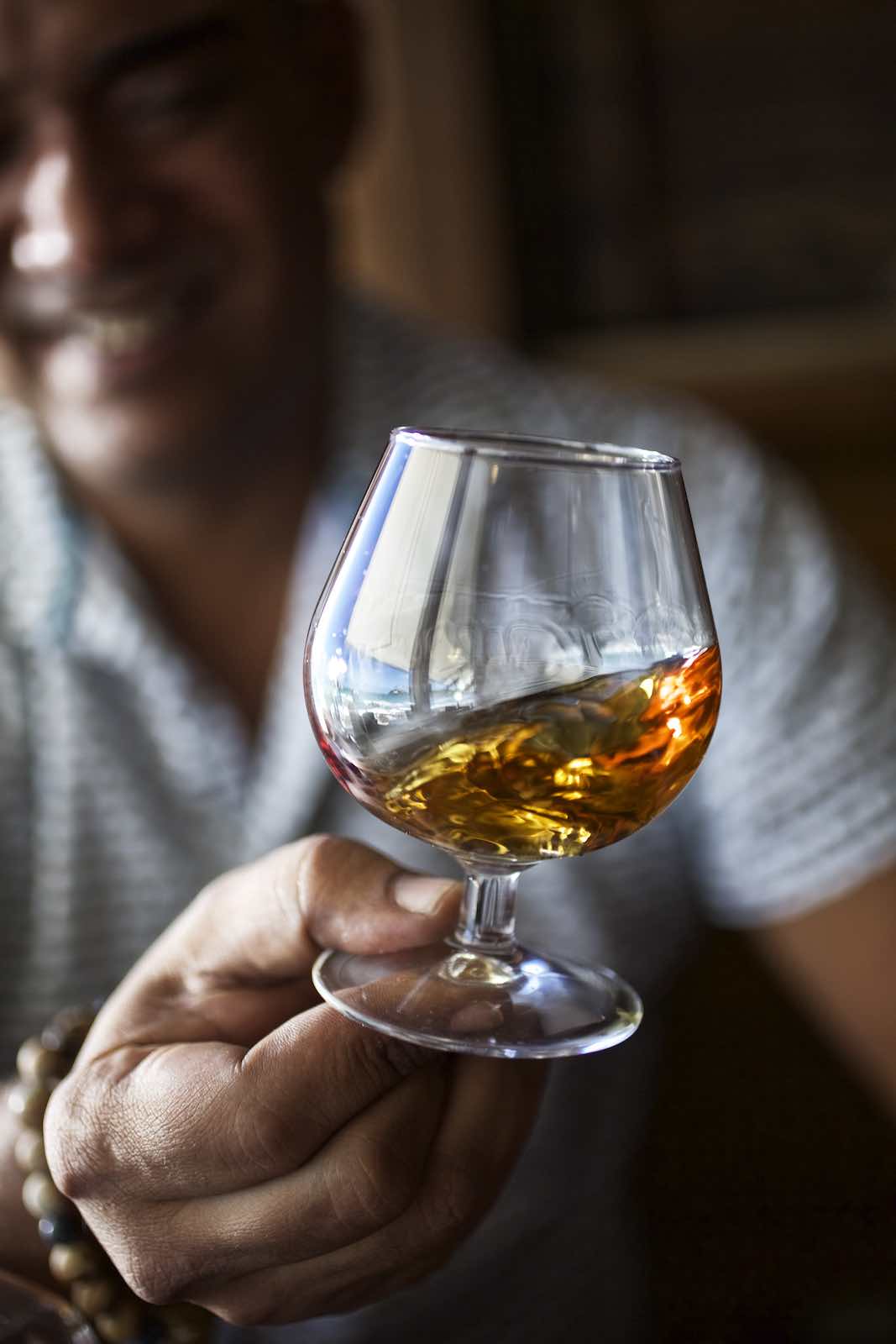 Jody Horton Photography - Man swirling rum in a short stemware glass. 