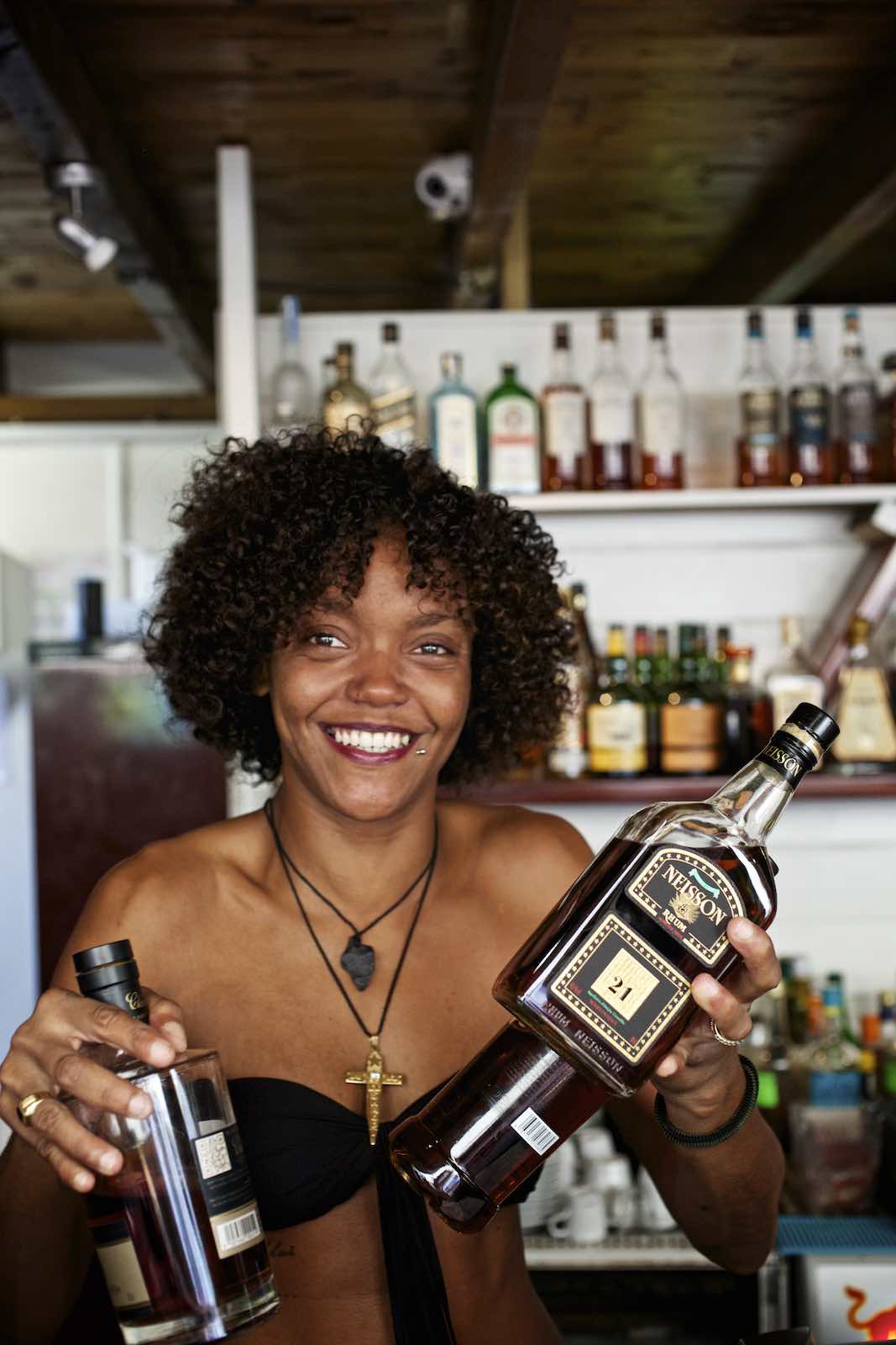 Jody Horton Photography - Bar tender smiling while holding three bottles of rum behind the bar. 