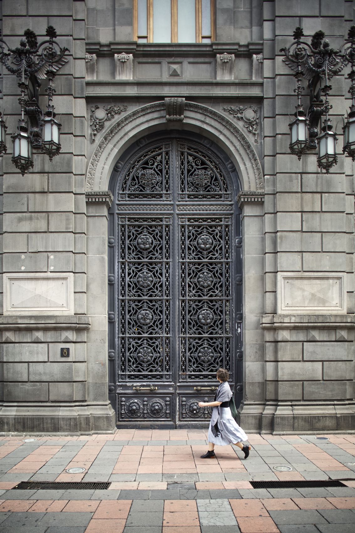 Woman walking in front of a large building in Mexico City. 