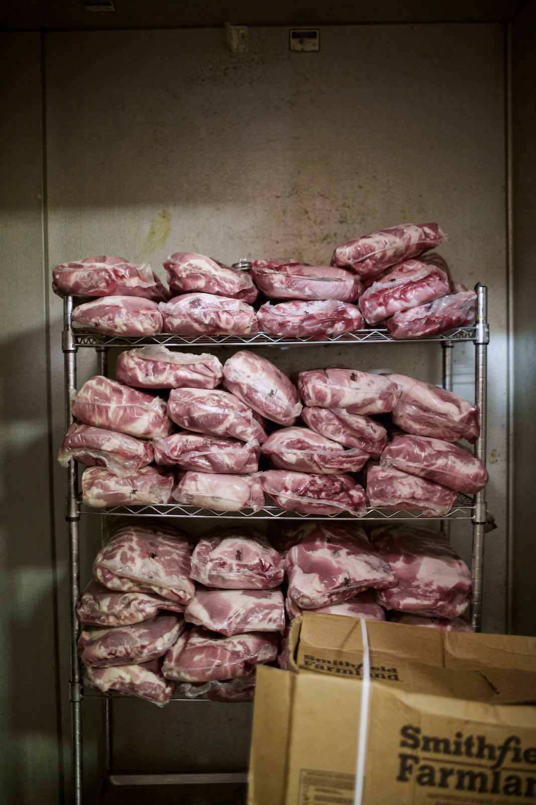 Jody Horton Photography - Vacuum packaged meats stacked on a metal kitchen rack. 