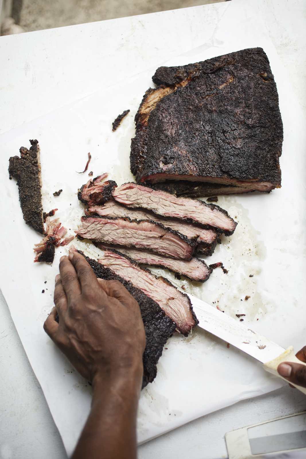 Jody Horton Photography - Smoked brisket being sliced on white parchment.  
