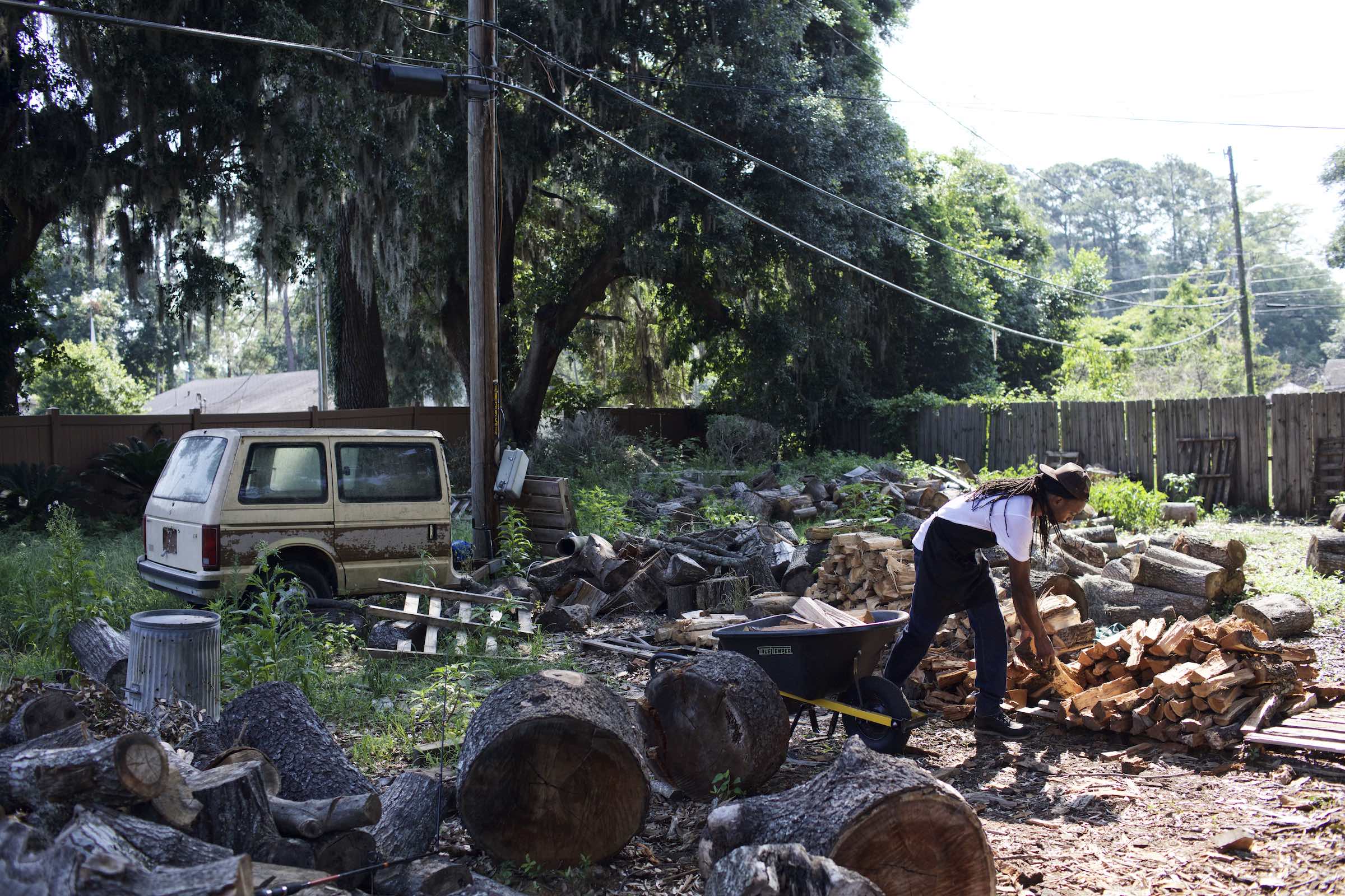 Jody Horton Photography - Chef chopping and piling wood in a lush yet disheveled yard. 