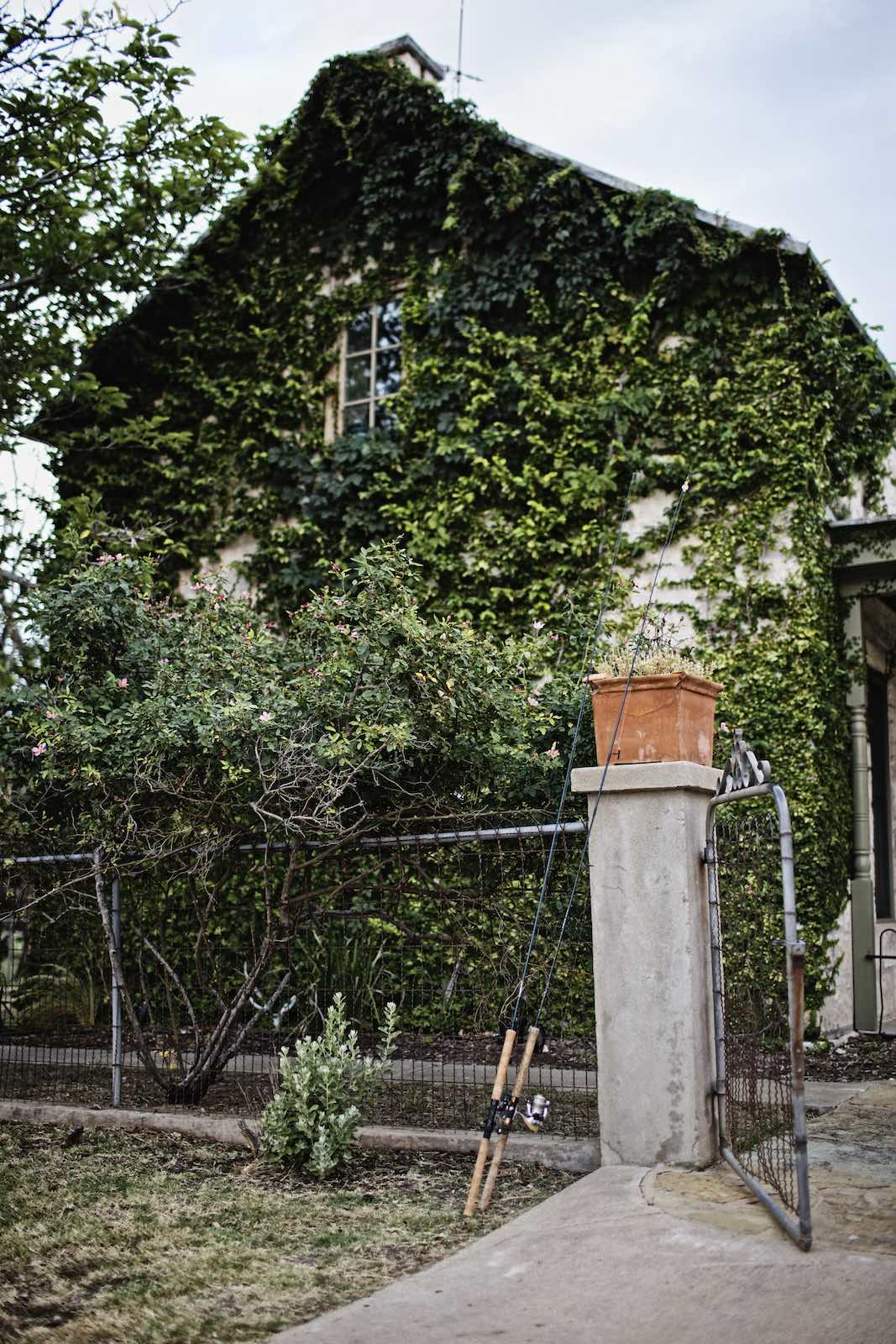 Jody Horton Photography - Fishing rods in front of a vine-covered cottage.
