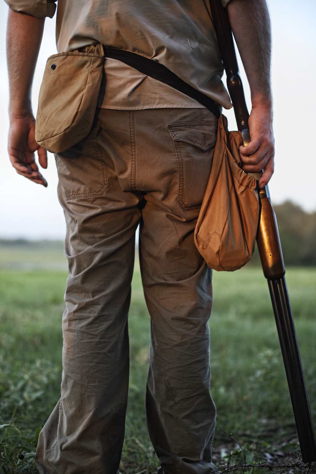 Jody Horton Photography - Hunter standing in grass with his rifle beside his leg. 