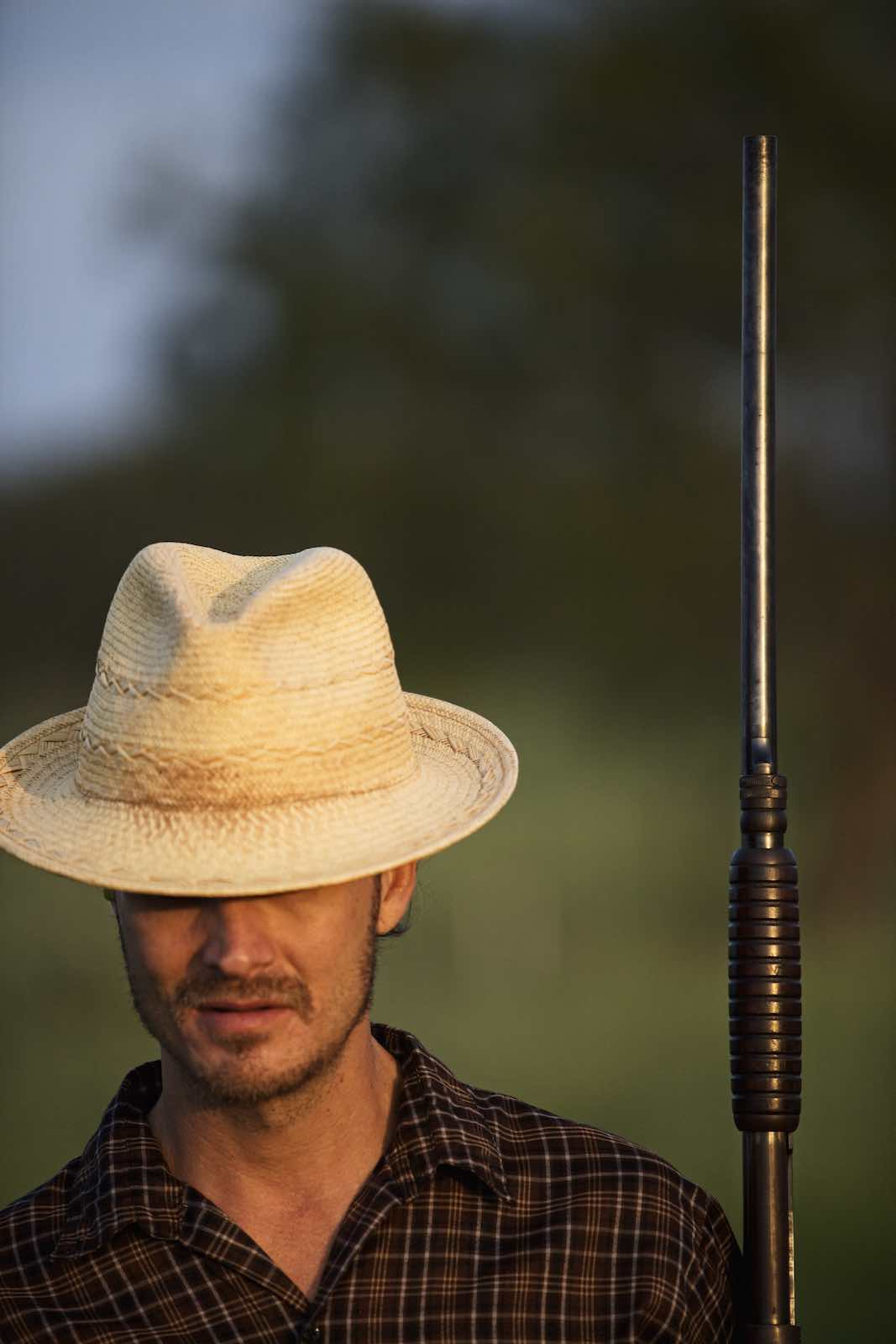 Jody Horton Photography - Hunter is a straw hat carrying his rifle parallel to his body.