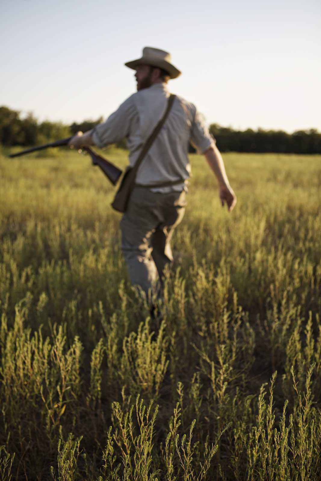 Jody Horton Photography - Chef Jesse walking though grasses with his rifle. 