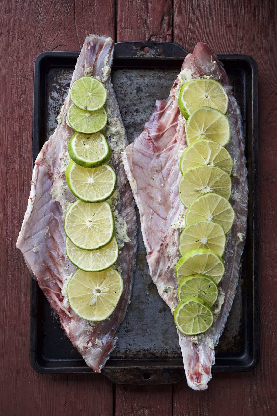 Jody Horton Photography - Large fish fillets with sliced limes on a metal tray.