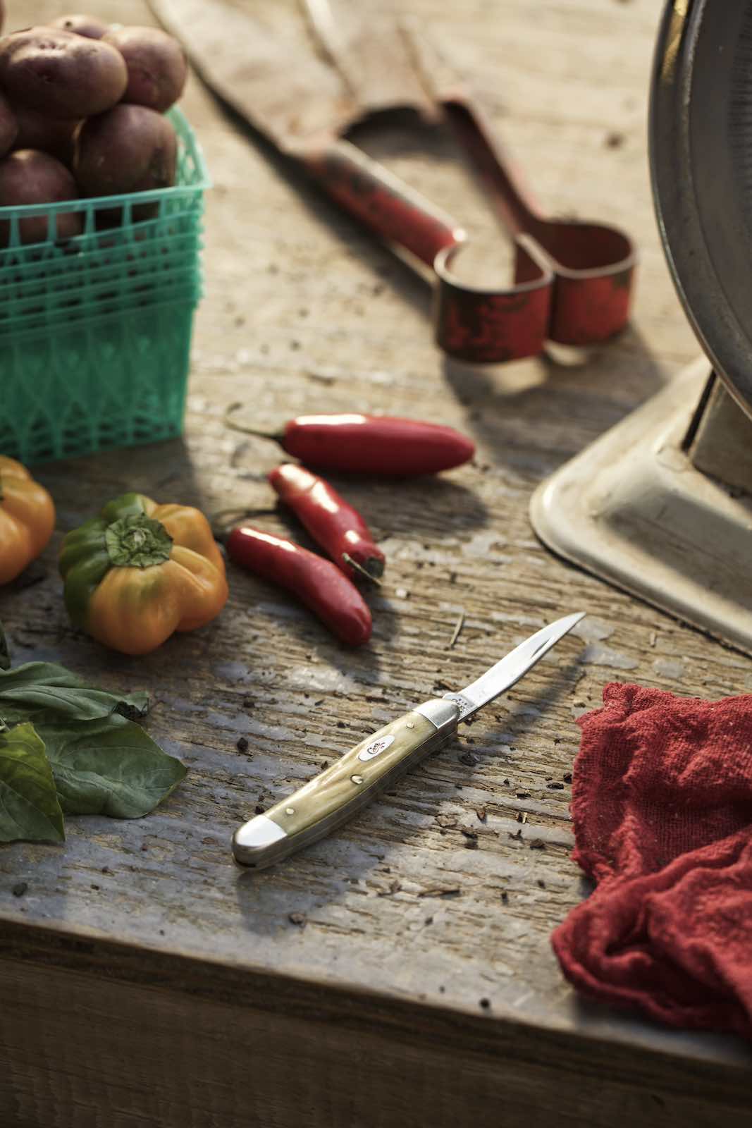Jody Horton Photography - Assorted peppers and a small pairing knife on a wood table. 