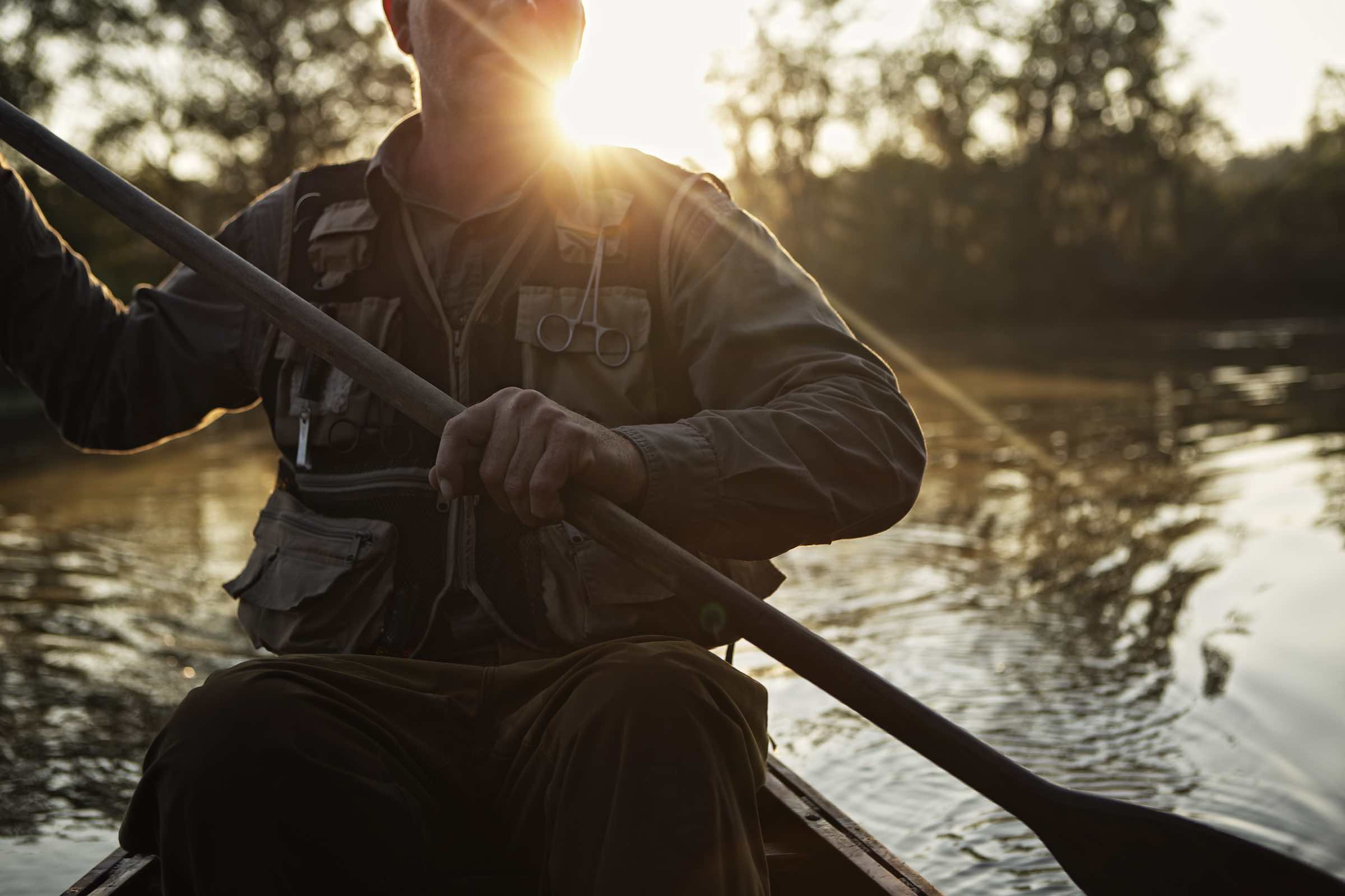 Jody Horton Photography - Canoer holding an oar with the evening sun behind him. 