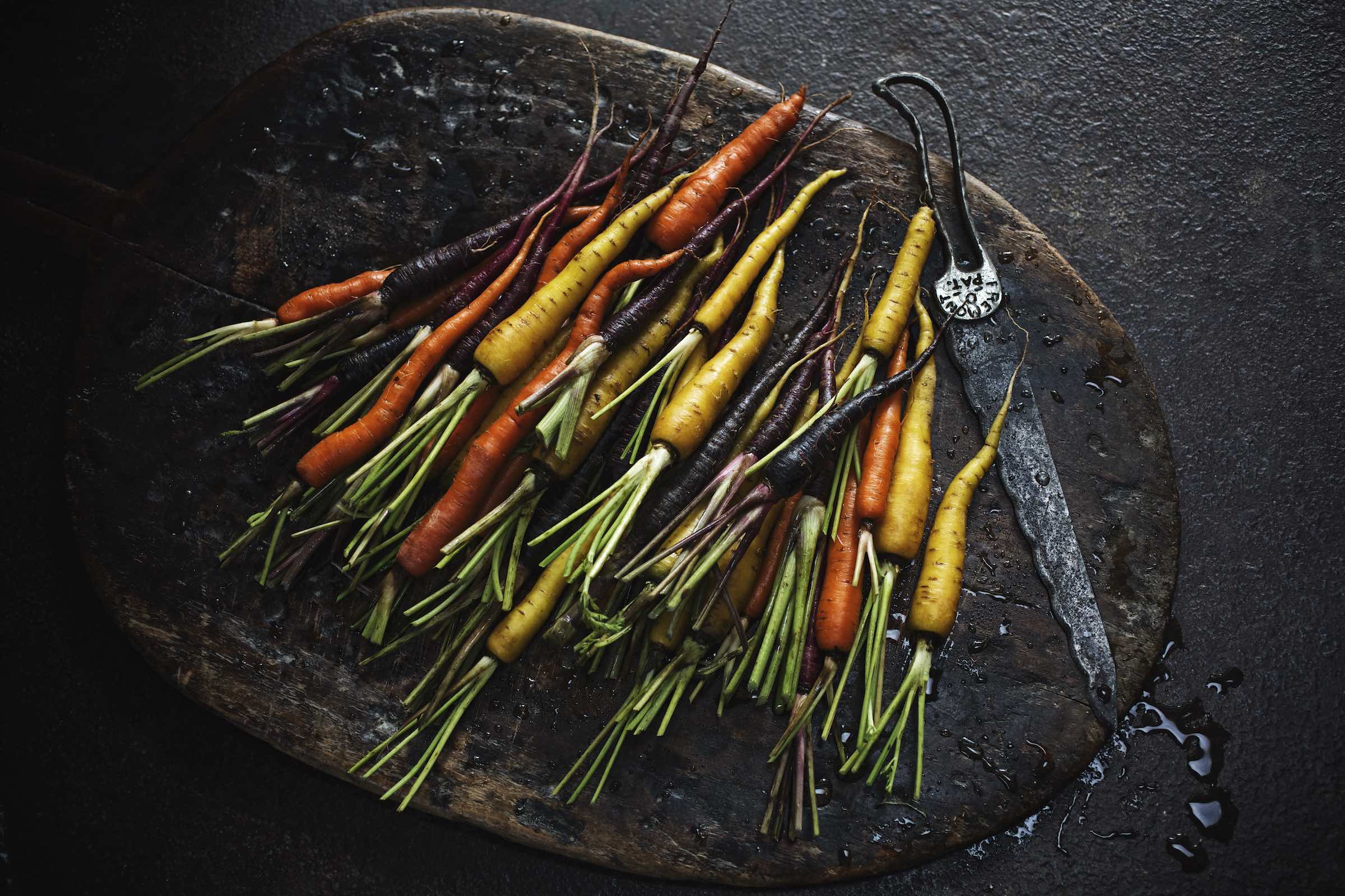 Jody Horton Photography - Rainbow carrots prepared on a rustic wood cutting board.