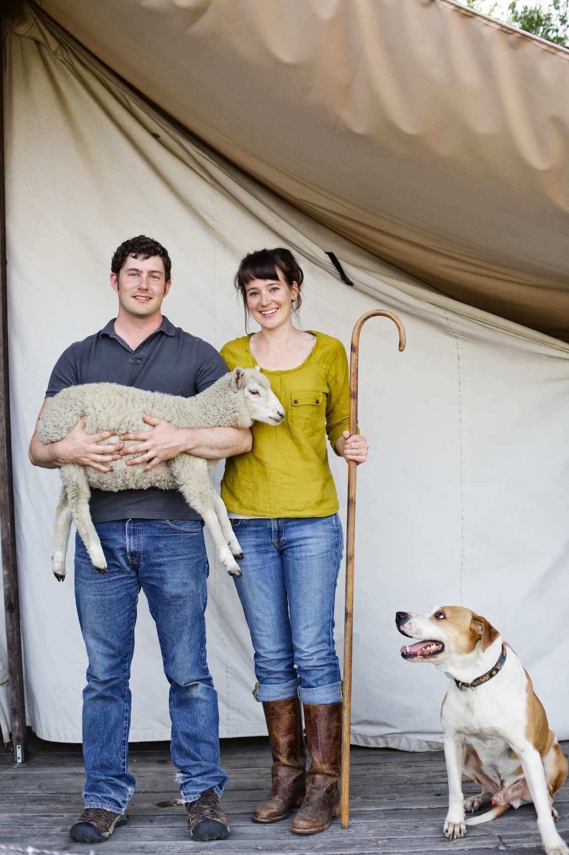 Jody Horton Photography - Farmers standing while holding a lamb, with their dog. 