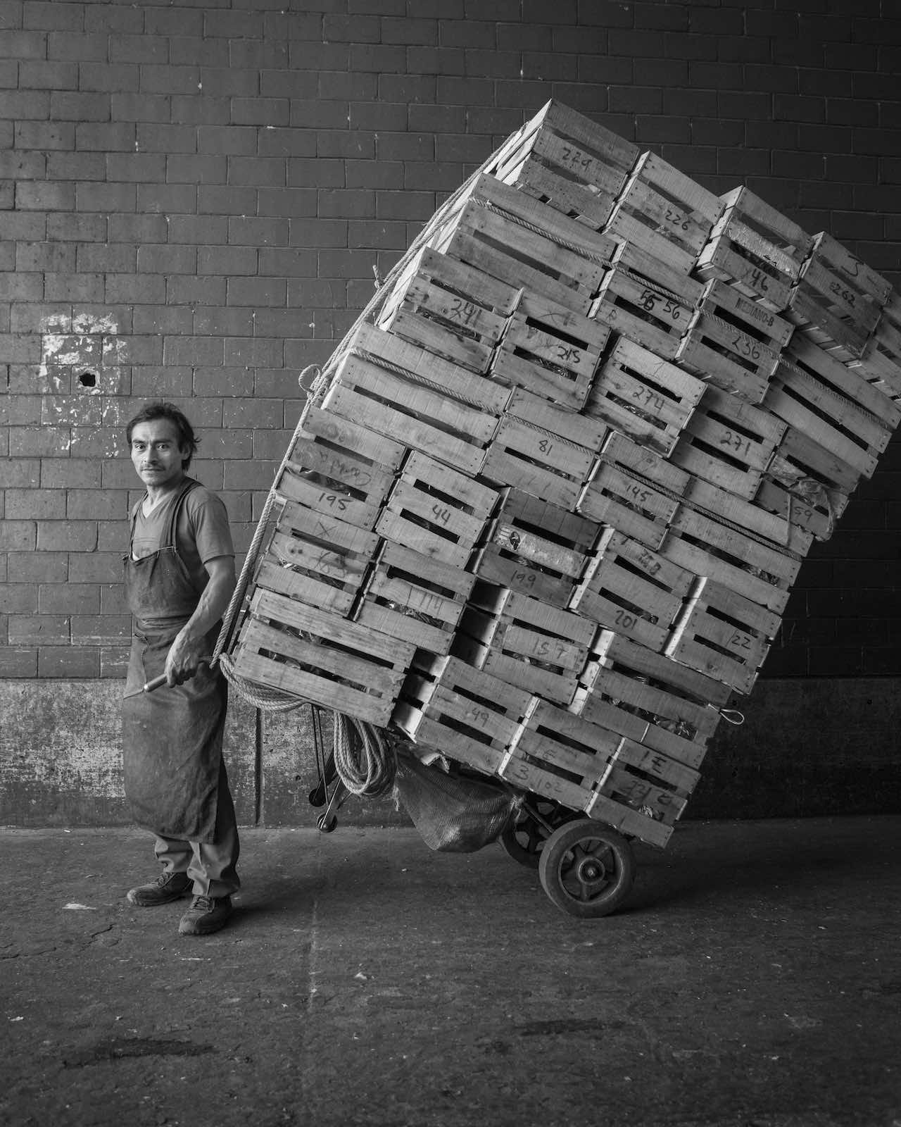 Jody Horton Photography - Vendor hauling crates of food through the open market, shot in B&W. 