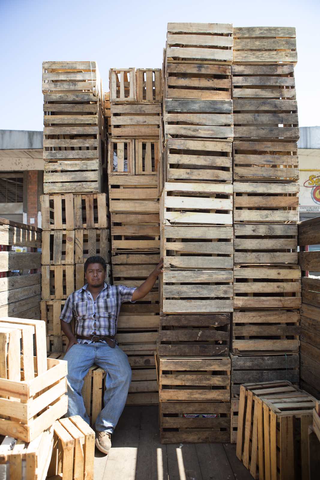 Jody Horton Photography - Man sitting in the shade of the stacks of empty crates. 