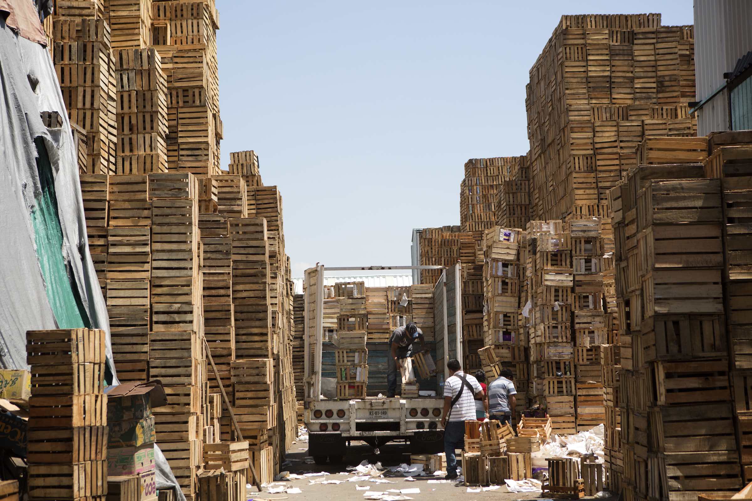 Jody Horton Photography - Men unloading empty crates from a truck and stacking them into towers. 