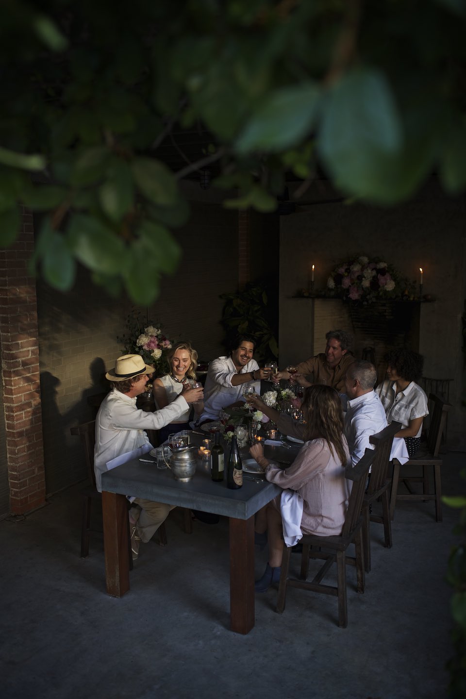 Evening gathering of friends cheersing at a large dinner table. 