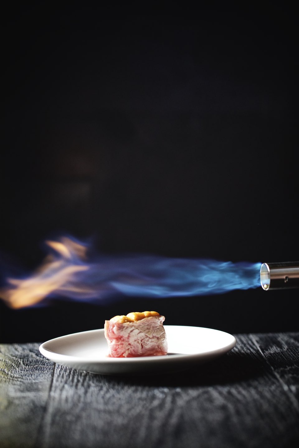 Torch and sushi on a black wood table. 