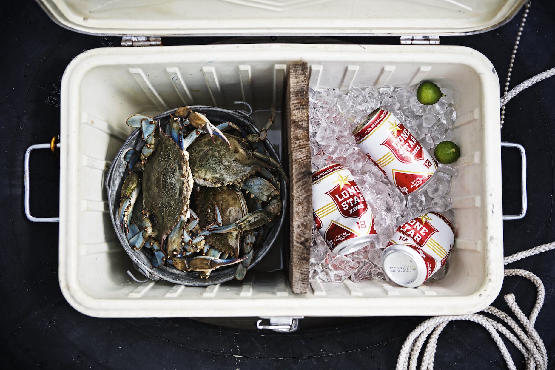 Cooler filled with whole, blue crabs and cans of Lonestar. 