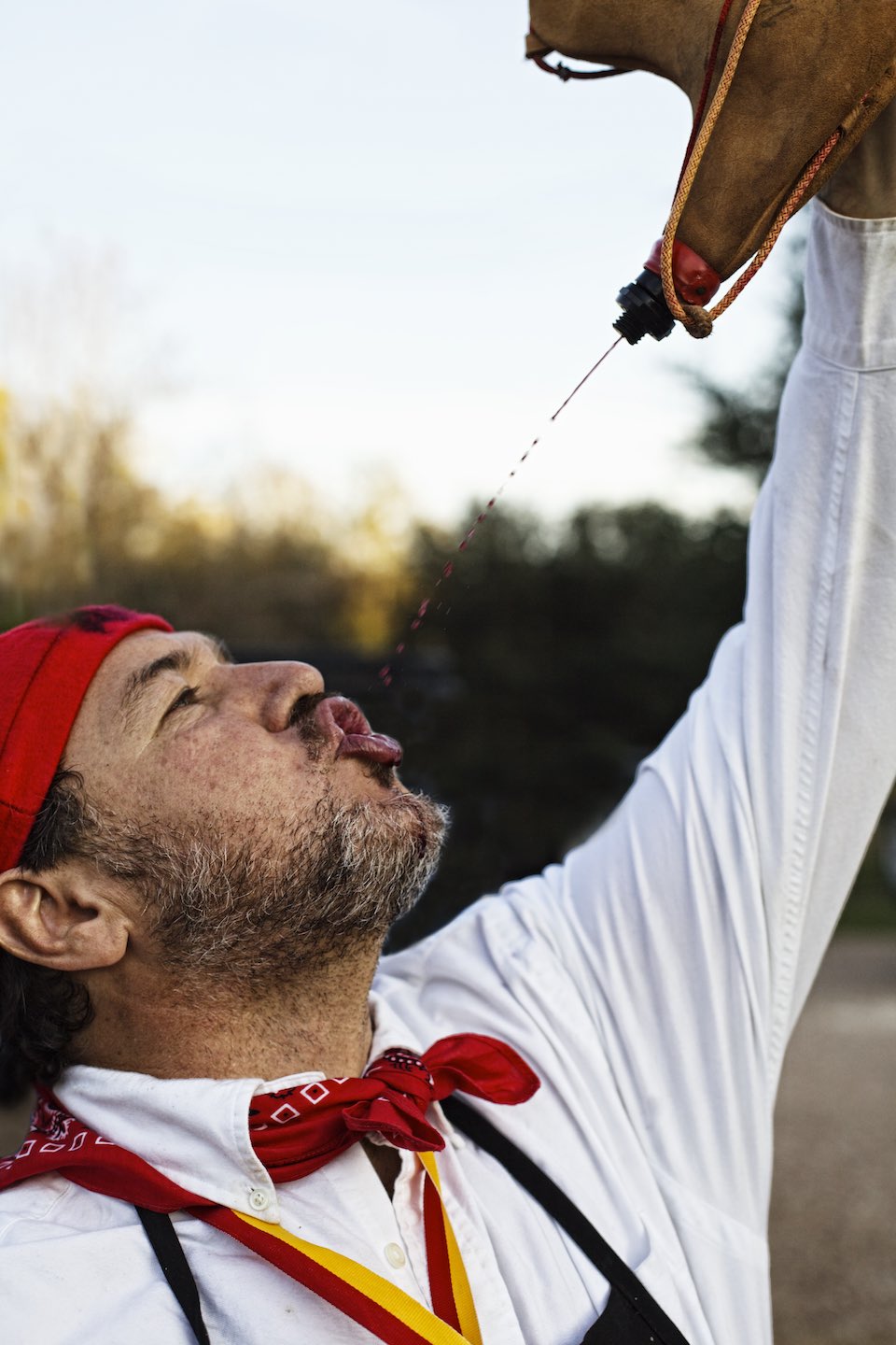Man pouring wine from a bota bag into his mouth. 