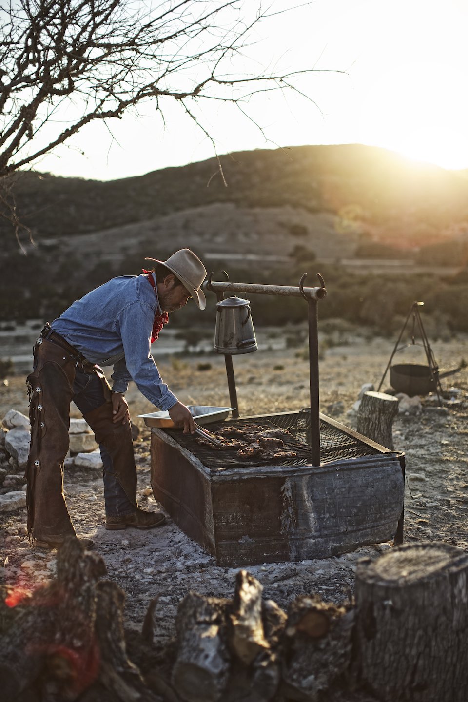 Cowboy cooking on an outdoor grill at sunset. 