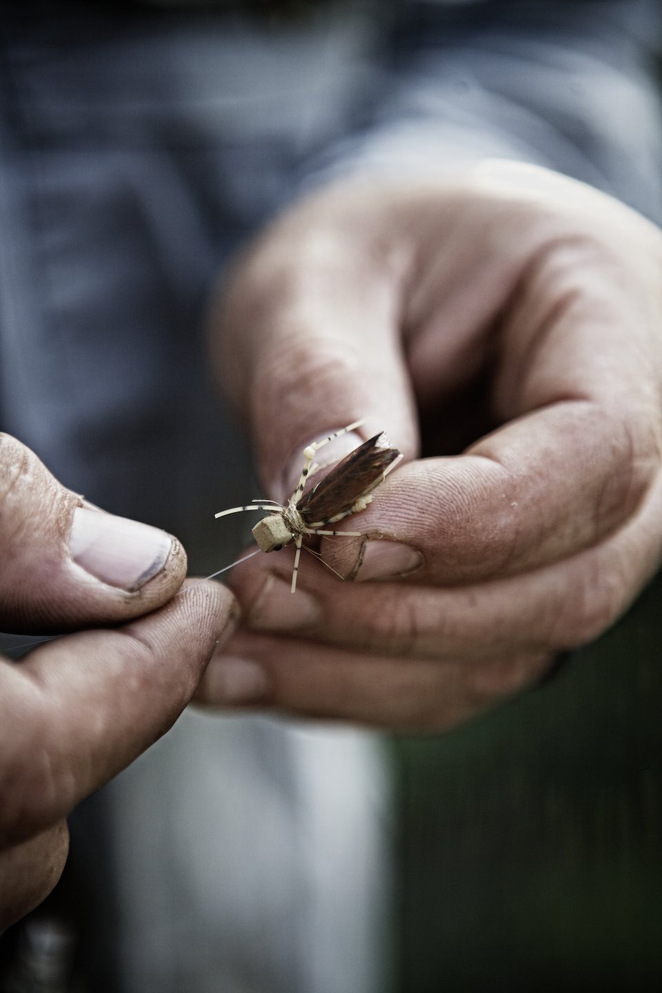 hands assembling a bug-like fishing lure. 