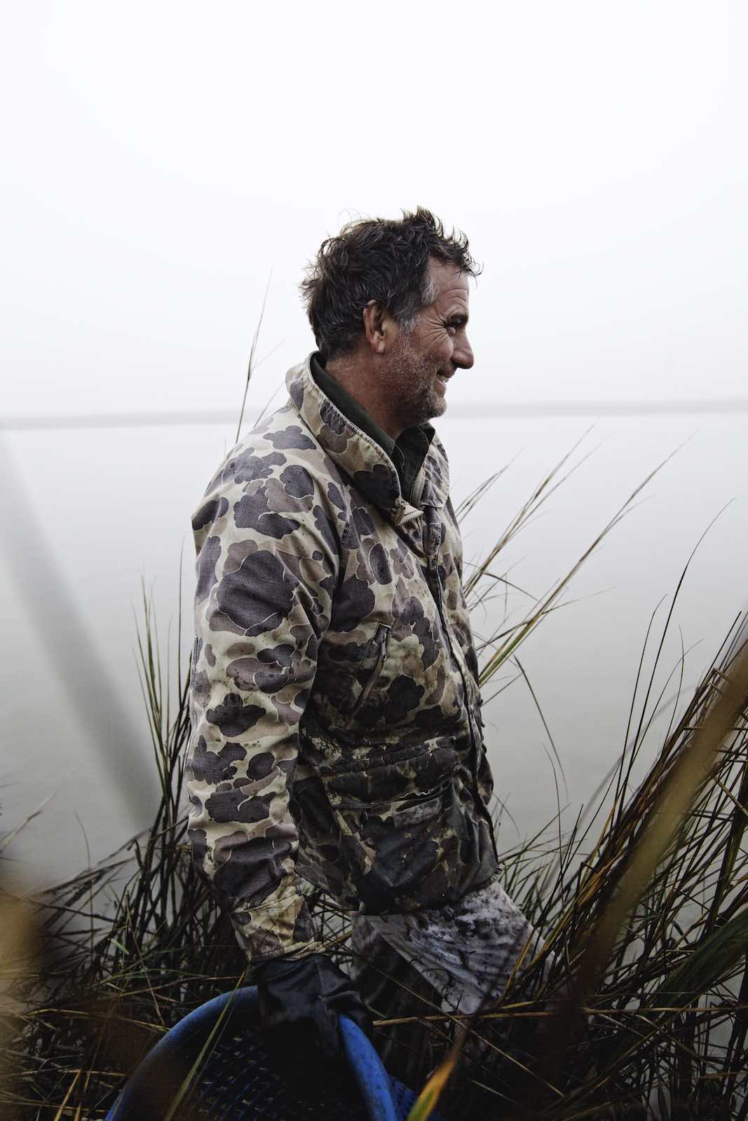 Jody Horton Photography - Fisherman walking through tall grass during oyster harvest. 