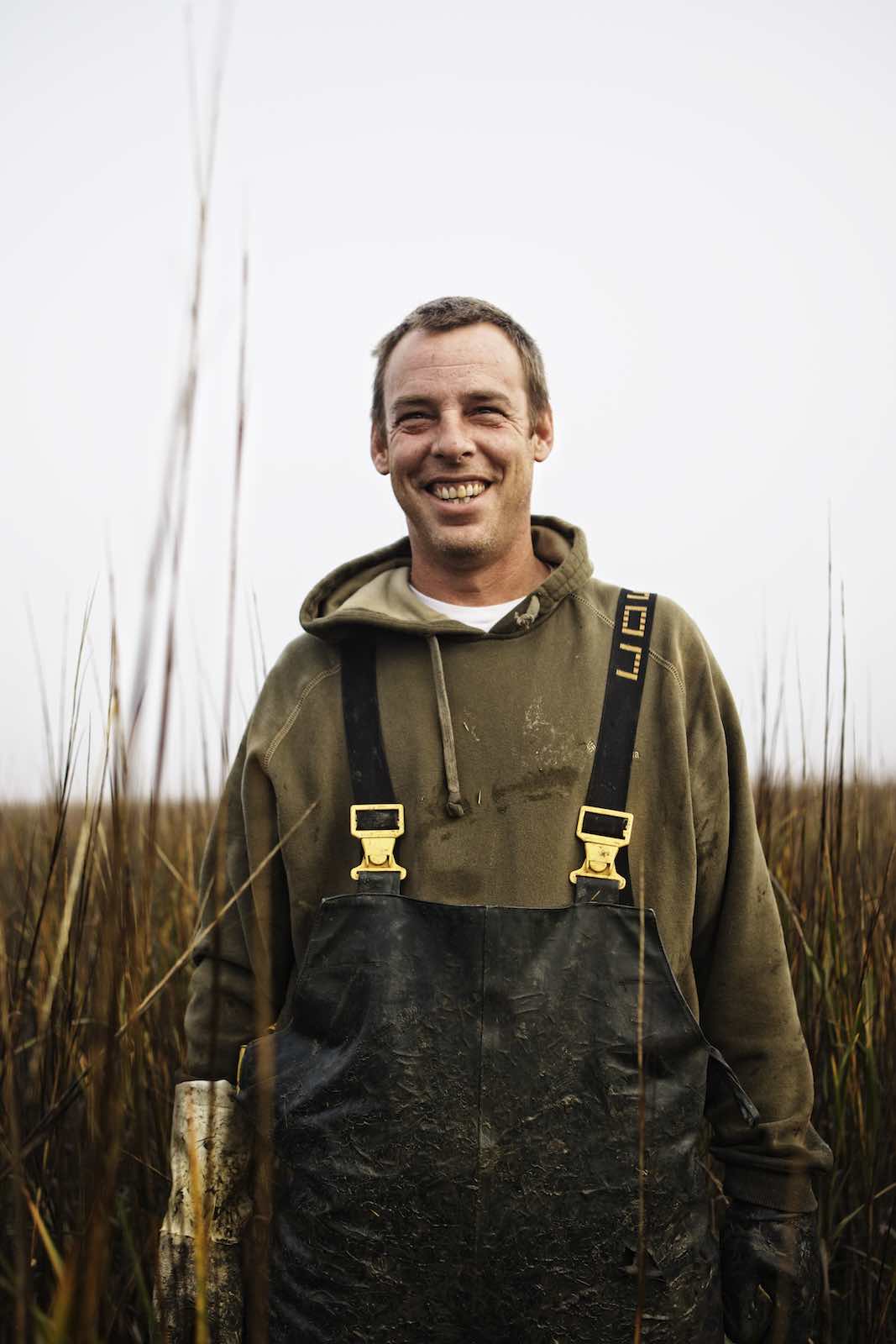 Jody Horton Photography - Fisherman standing in marsh grasses and smiling. 