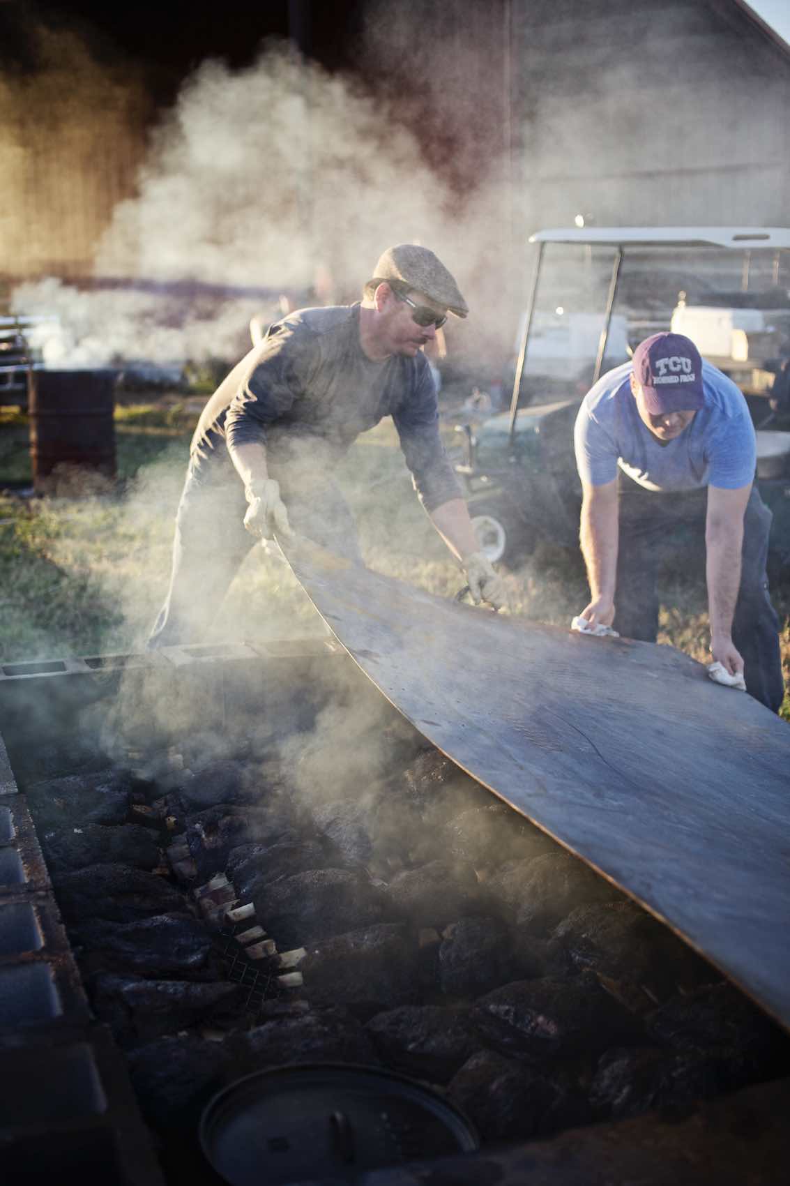 Jody Horton Photography - Men work together to uncover large outdoor barbecue pit. 