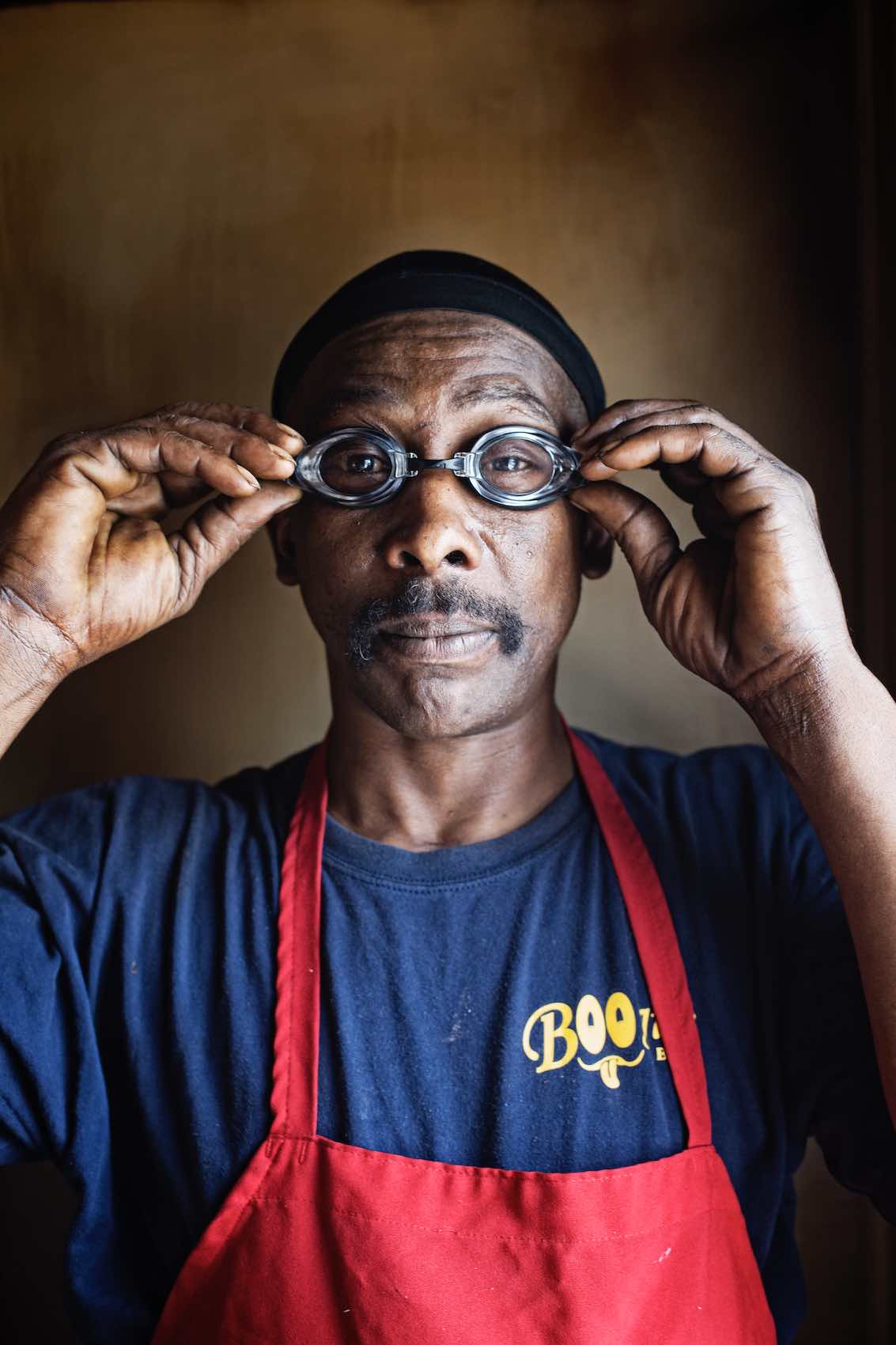 Jody Horton Photography - Portrait of man in red apron putting on goggles.