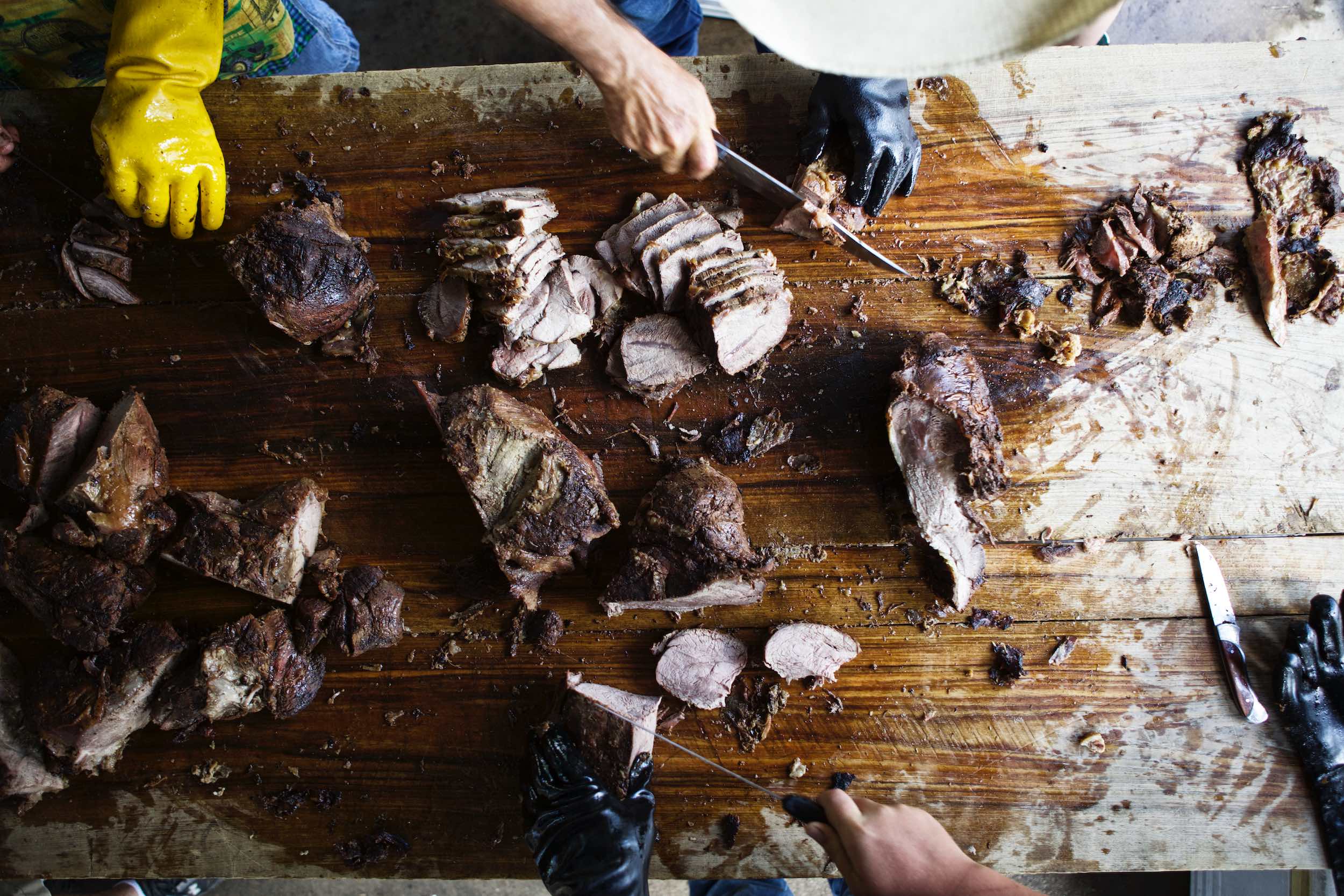 Jody Horton Photography - Smoked meats prepared and sliced on large wood table.