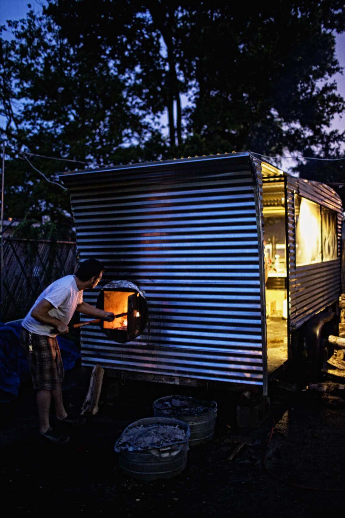 Jody Horton Photography - Man stoking fire outside trailer. 