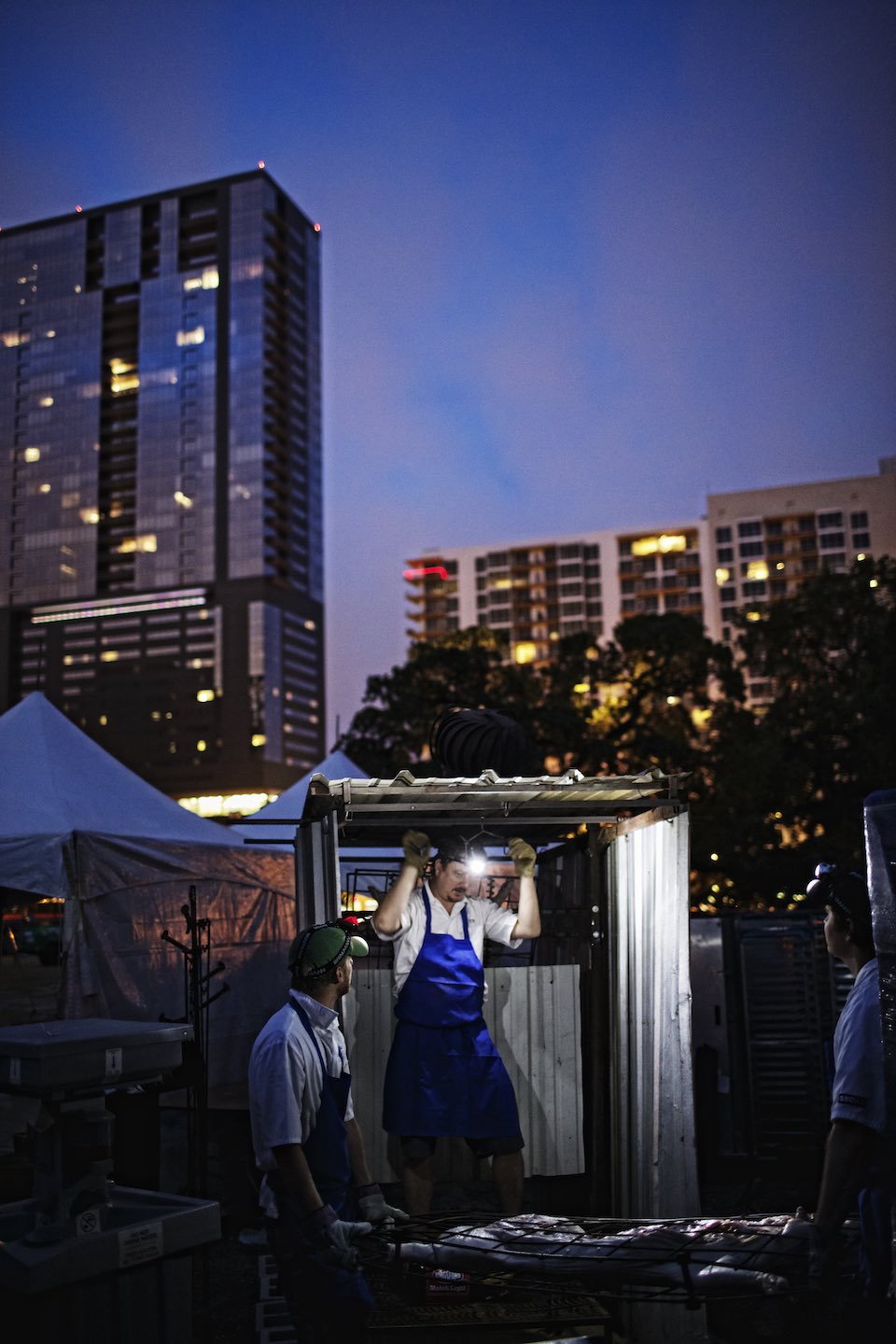 Jody Horton Photography - Chef Tim Byres preparing the pig for the roast, with the Austin skyline in the background.