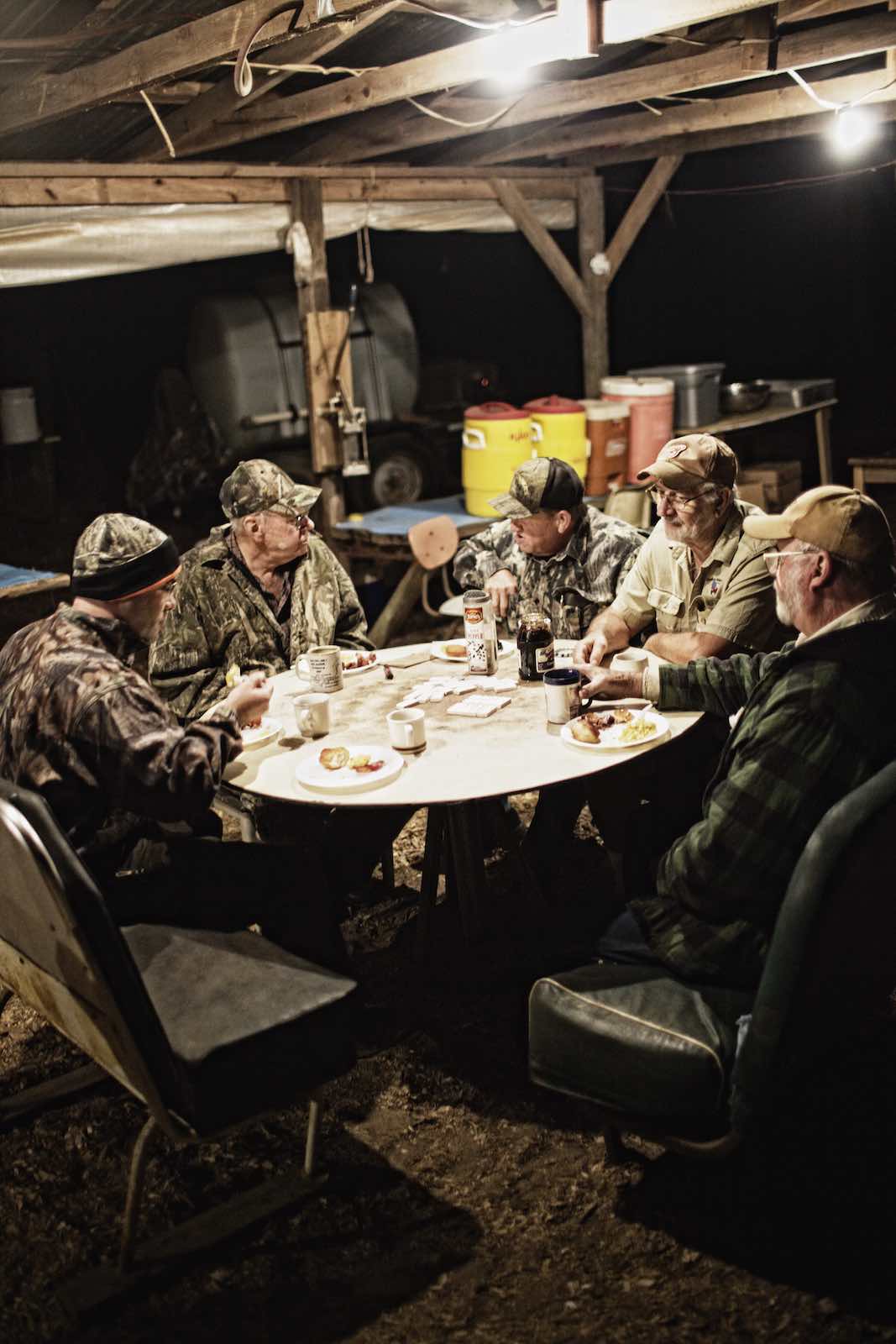 Jody Horton Photography - Hunters eating at a round table in the dark, early hours of the morning.