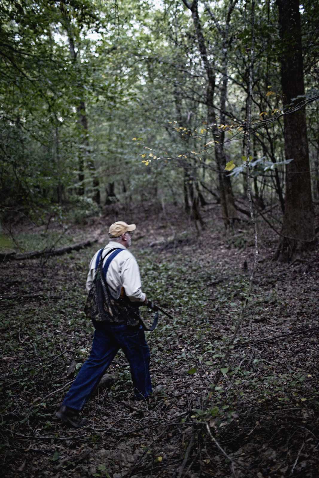 Jody Horton Photography - Hunter carrying a long shot gun through dense woods. 