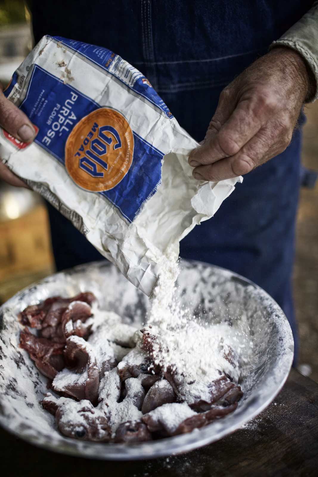 Jody Horton Photography - Flour pouring on squirrel meat in a metal bowl. 