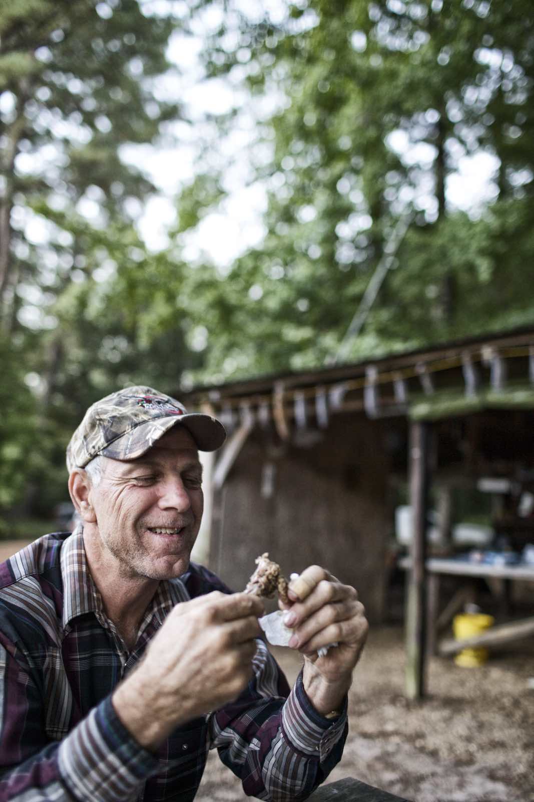 Jody Horton Photography - Hunter sitting outside and eating squirrel meat. 